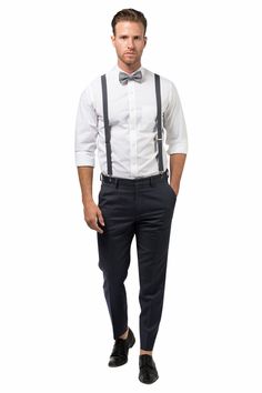 a man in a white shirt and black bow tie is standing with his hands in his pockets