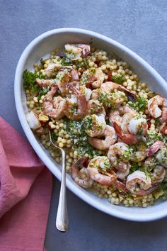a white bowl filled with shrimp, broccoli and corn on top of a pink napkin