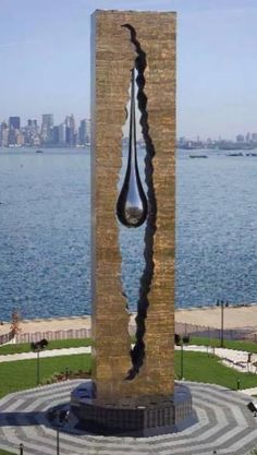 a sculpture in the shape of a tear on top of a building next to a body of water