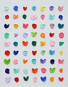 many different colored paper hearts on a white surface with one being cut into smaller pieces