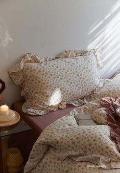 an unmade bed with two pillows and a lit candle
