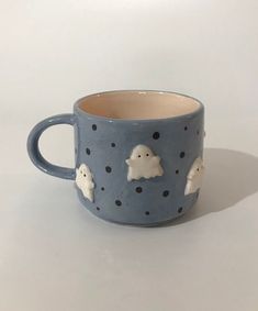 a ceramic mug with some little white ghost on it's side and black dots