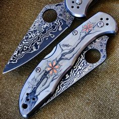 two knifes with designs on them sitting next to each other
