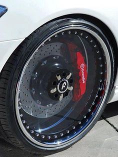 the front wheel of a white car with black spokes and red brake pads on it