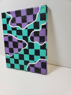 a purple and black checkered painting sitting on top of a white table