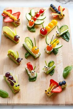 a wooden cutting board topped with cut up vegetables and bugs on top of each other