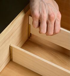 a hand reaching into a drawer to open it