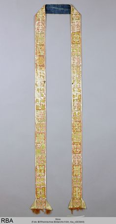 two pieces of cloth with gold and blue designs on them, one is folded in the shape of an arrow