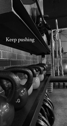 kettles are lined up on a shelf in a gym with the words keep pushing above them