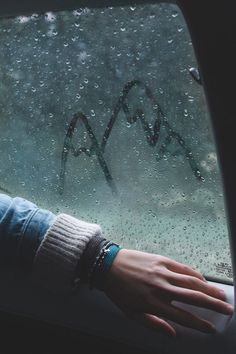 a person's hand on the windshield of a car with graffiti written on it