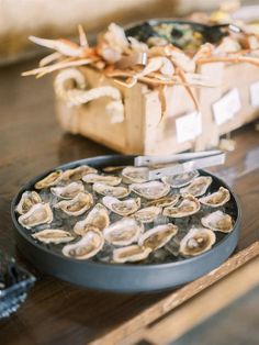 an assortment of raw oysters on a wooden table next to a box of seaweed