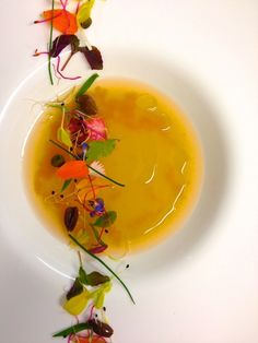 a white plate topped with yellow liquid and flowers