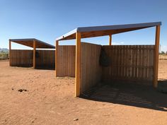 two wooden structures in the middle of a dirt field