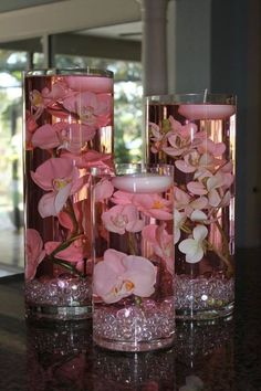 three vases filled with pink flowers on top of a table