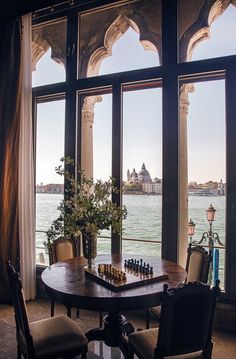 a chess game set up on a table in front of a window overlooking the water