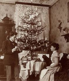 an old black and white photo of two women sitting in front of a christmas tree