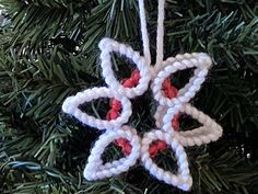 a crocheted ornament hanging from a christmas tree with red and white beads