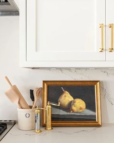 two pears on a table in front of a painting and kitchen utensils
