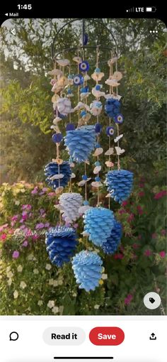 a wind chime hanging from the side of a tree in front of some flowers