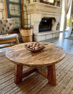 a bowl of nuts on top of a wooden table in front of a fire place