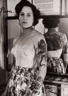 a woman standing in front of a mirror with tattoos on her arms and shoulder,