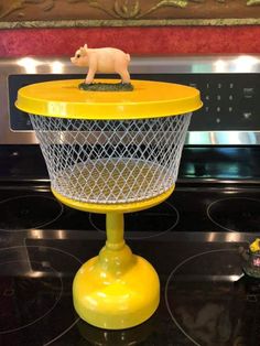 a toy pig is sitting on top of a wire basket in front of an oven