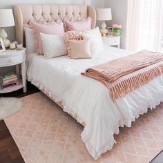 a white bed with pink pillows and blankets