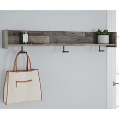 a white bag hanging on a wall next to a wooden shelf with two purses