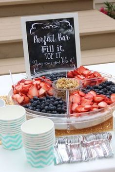 a table topped with plates and cups filled with fruit next to a sign that says parfait kabob fill it too
