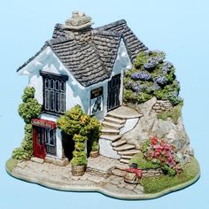 a small house on top of a rock with flowers growing out of the windows and steps leading up to it