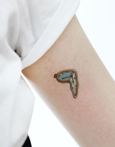 a person with a tattoo on their arm has a blue and brown object in the shape of a letter