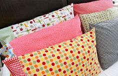 four pillows are stacked on top of each other in different colors and patterns, along with a black headboard