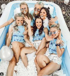a group of women sitting on top of an inflatable pool filled with white foam