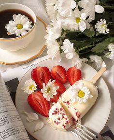 strawberries and cream on a plate next to a cup of coffee with flowers in the background