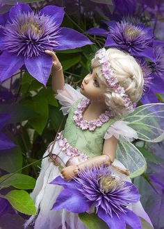 a fairy doll sitting on top of purple flowers