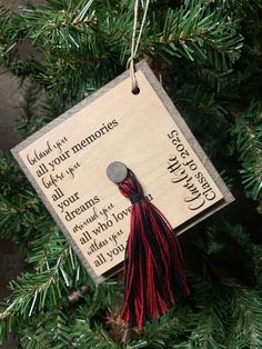 a wooden ornament hanging from a christmas tree with a tassel on it