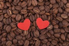 two red hearts sitting on top of coffee beans