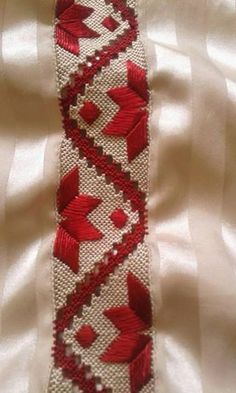 a red and white tie is laying on top of a white cloth covered bed sheet