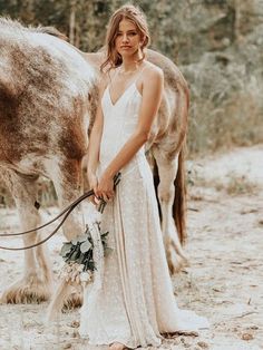 a woman standing in front of a horse with a bridal bouquet on her hand