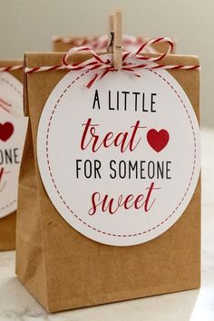 two brown paper bags with red and white tags on them, one says a little treat for someone sweet