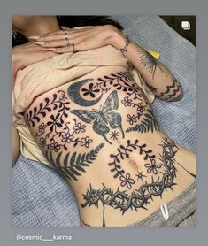 a woman laying on top of a bed with tattoos on her stomach and back legs