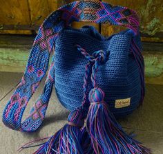 a crocheted blue bag with tassels on it