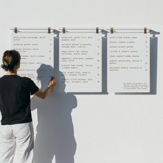 a person writing on a white wall next to three plaques with words written on them