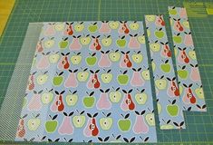 two pieces of fabric with apples on them next to a cutting board and rulers