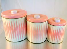 three pink and white canisters sitting on top of a table