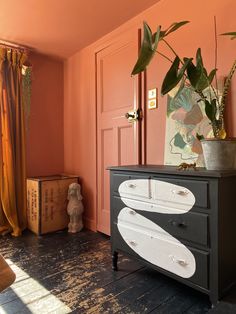 a black dresser with white surfboard painted on it in a pink room next to a door