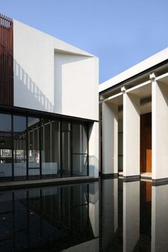 an empty pool in front of a white building with columns and glass doors on the outside