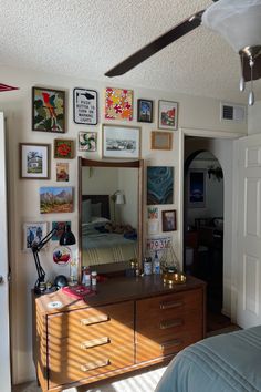 a bedroom with pictures on the wall and a dresser in front of it's mirror