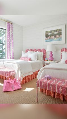 two beds with pink and white bedding in a bedroom next to a large window