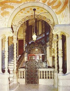 an ornate entry way to a building with stairs and arches on the sides, painted in gold and white